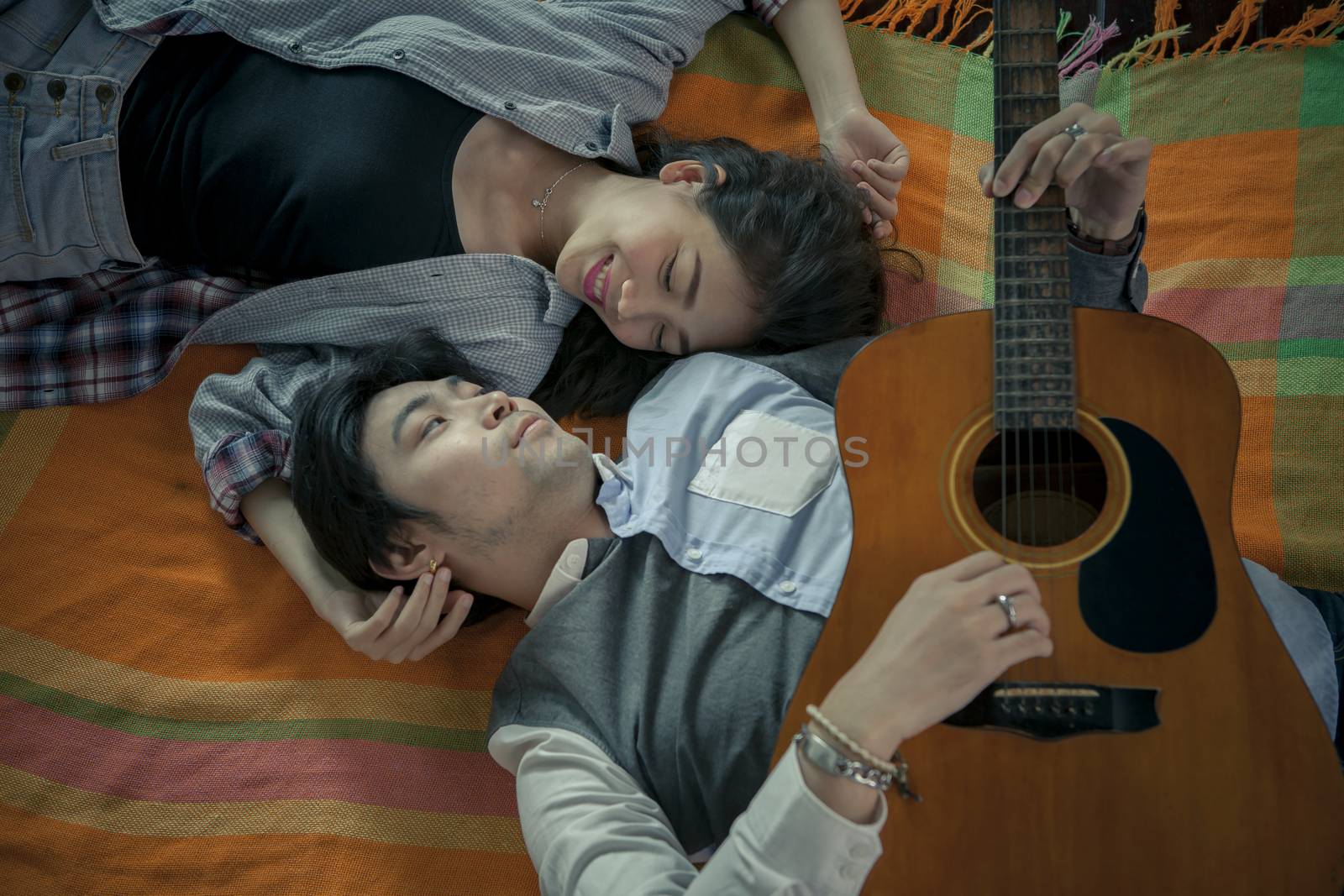 couples of asian younger man and woman playing guitar with relaxing and happiness emotion