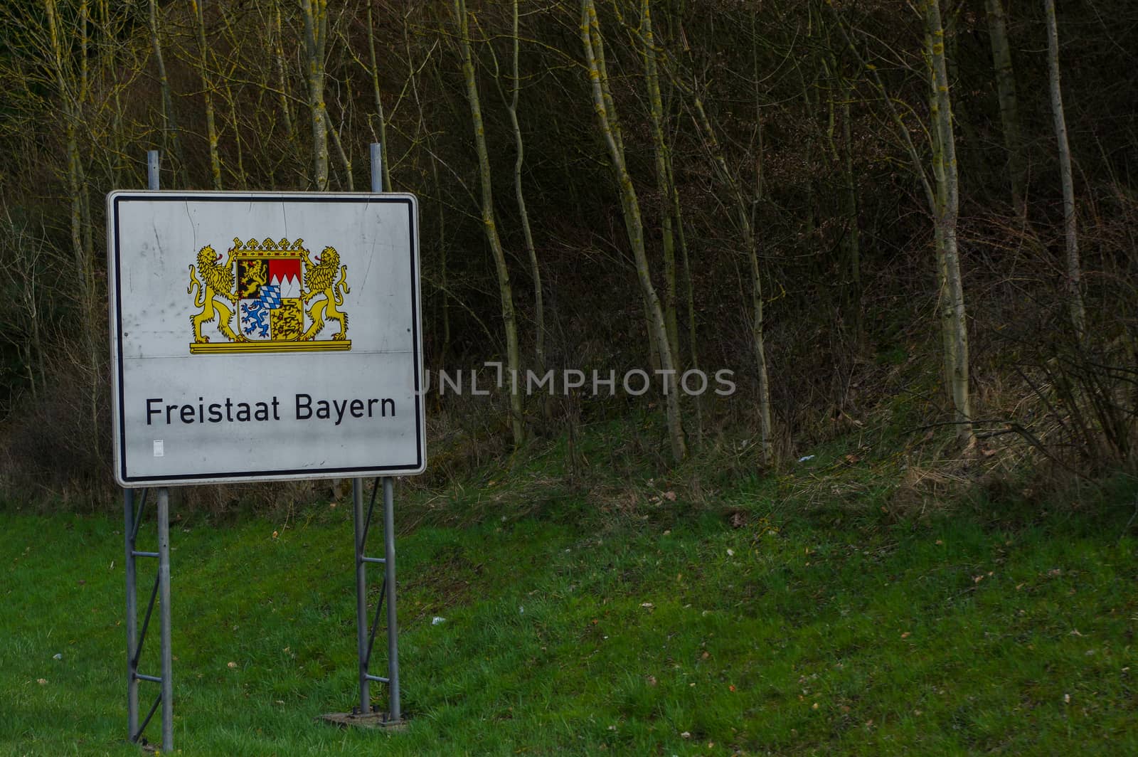a white highway border sign with coat of arms Bayern, Germany, translation in English: Freestate Bavaria