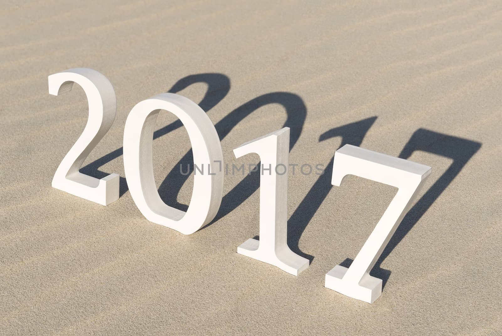 White wood figures on a beach forming the text two thousand seventeen as conceptual welcoming of the coming new year
