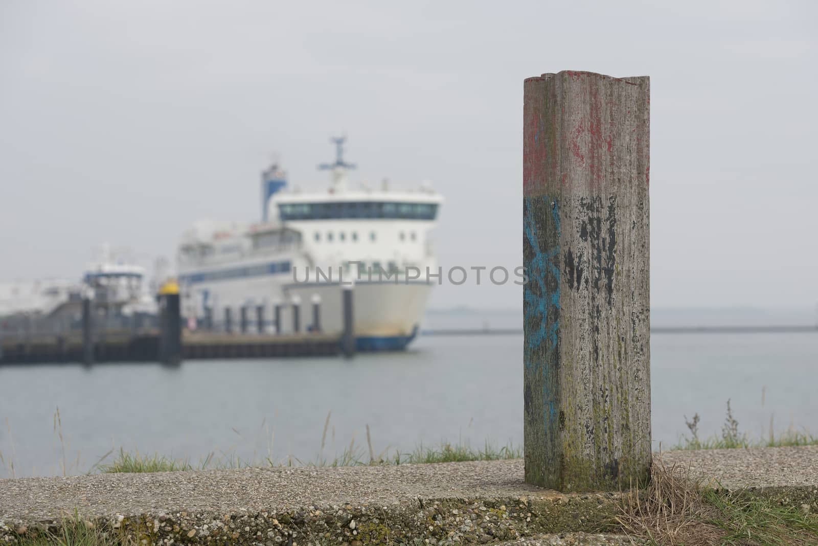 Bollard on the dike of Terschelling with a ferry in the background
