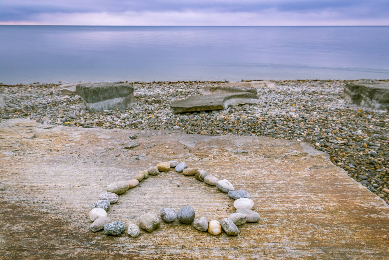 Image on the shore of the lake Bodensee, south Germany, with a heart made of stones and the beautiful blue lake and sky at the horizon