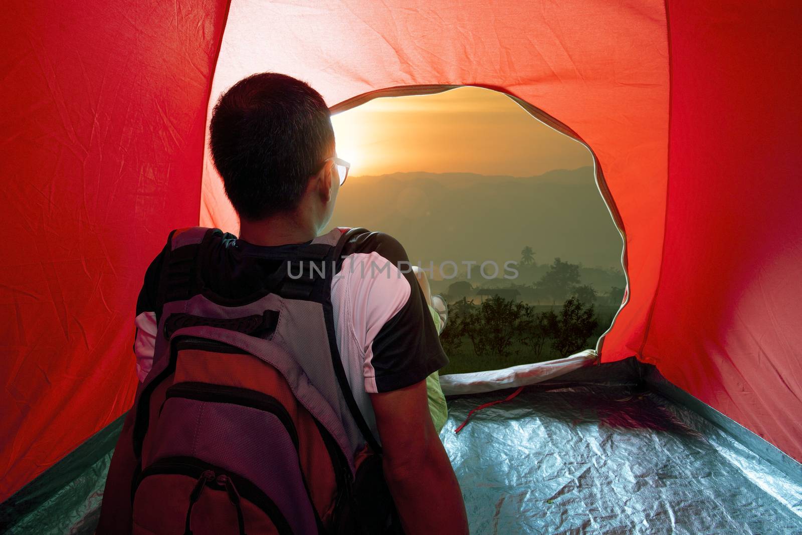 camping man in tent and sun rising sky