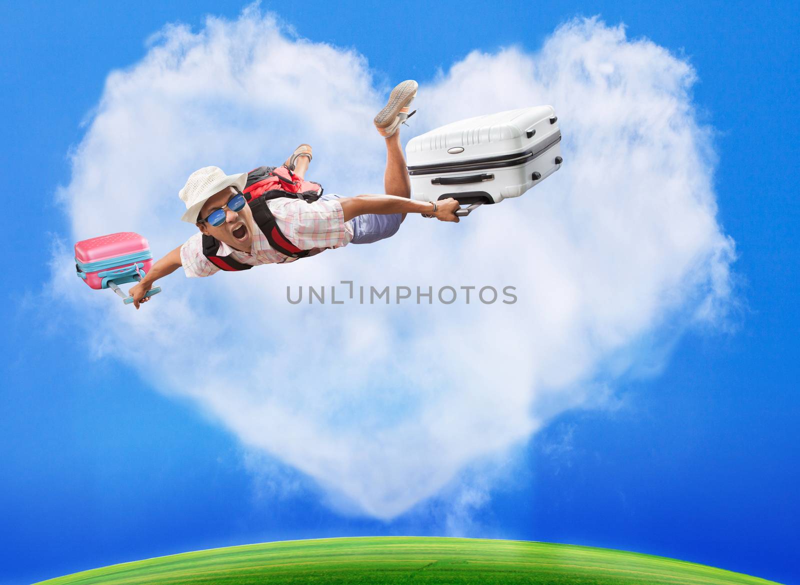 hand preparing to throwing paper plane to mid air againt green grass field and heart shape white clouds on clear blue sky 