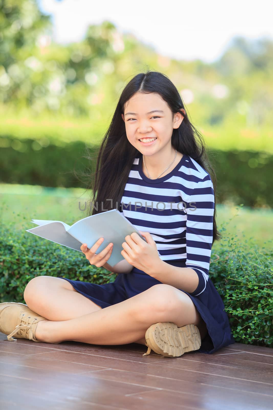 asian girl and school book in hand toothy smiling face with happ by khunaspix