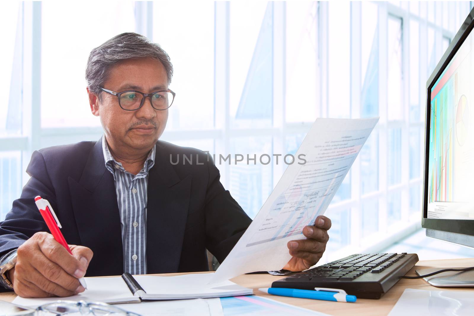 senior business man working on office table  with computer and business graph report ,writing and thinking solution planing