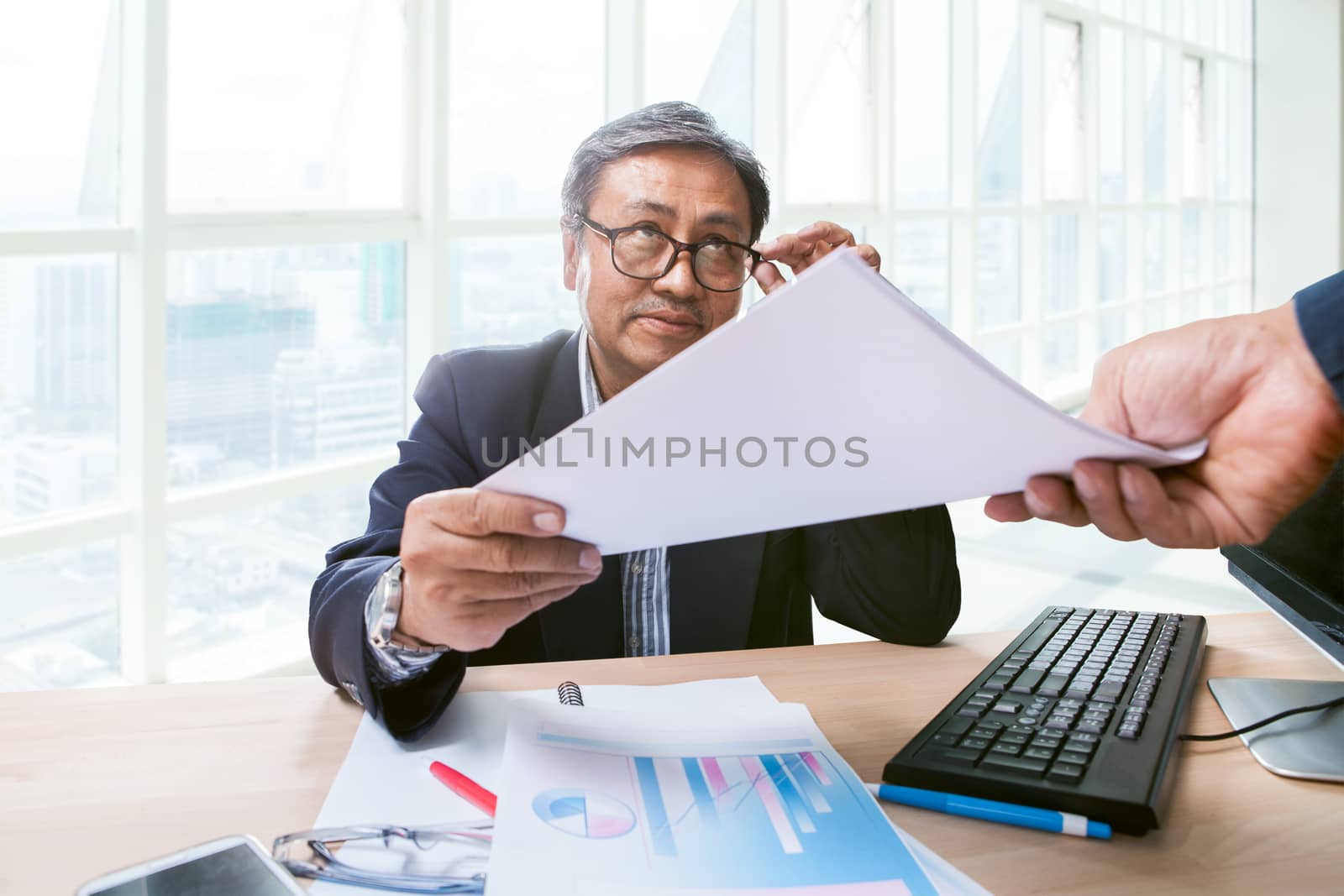 business man sitting in working table office and paper report in hand  smiling face to another