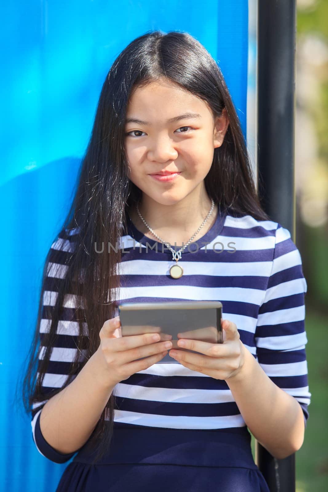 asian girl and computer tablet in hand standing with toothy smil by khunaspix