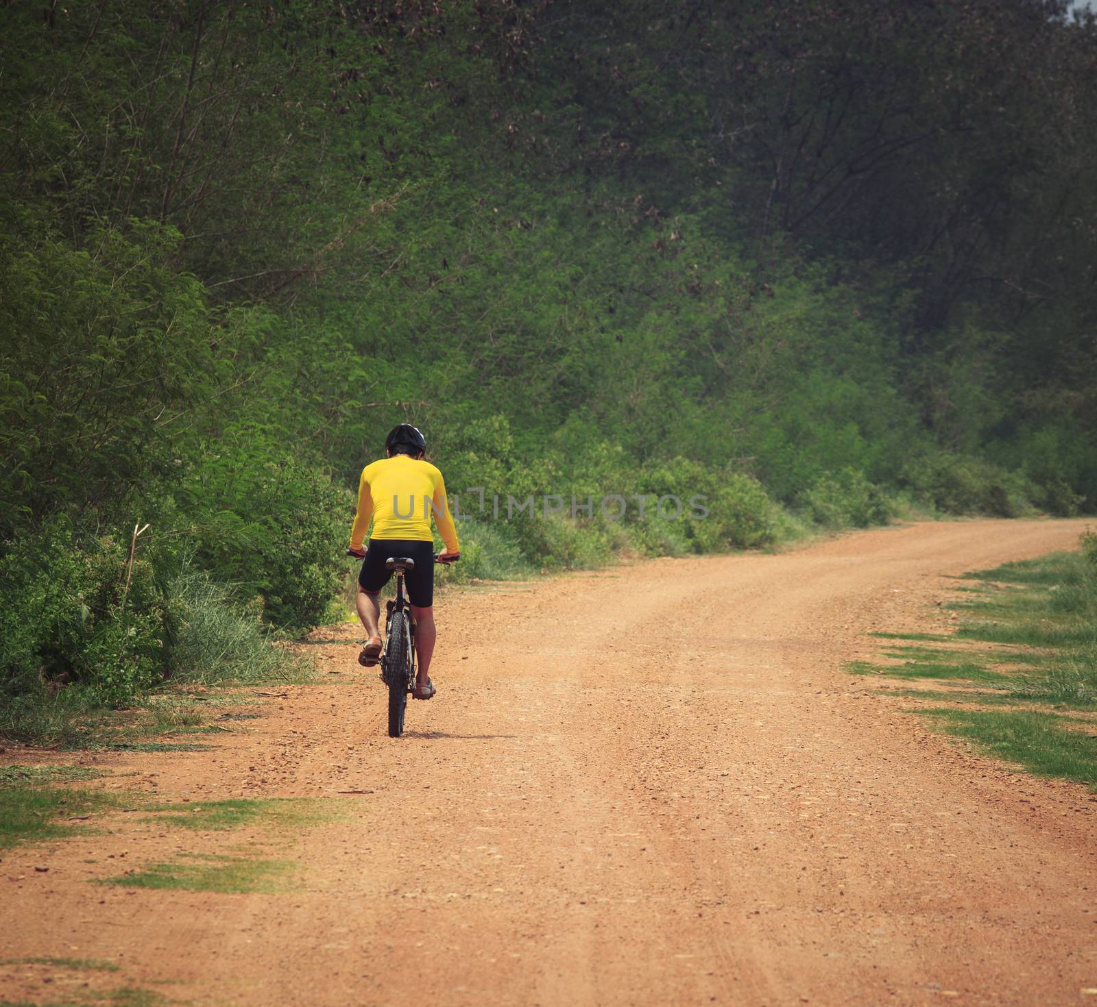 young man riding mountain bike in dusty road use for sport leisu by khunaspix