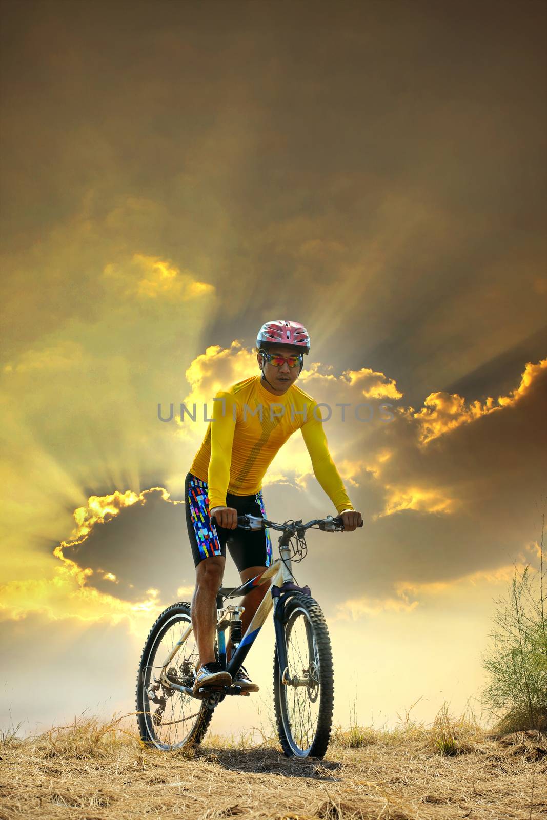 young man riding moutain bike mtb on land dune against dusky sky in evening background  use for sport leisure and out door activities theme