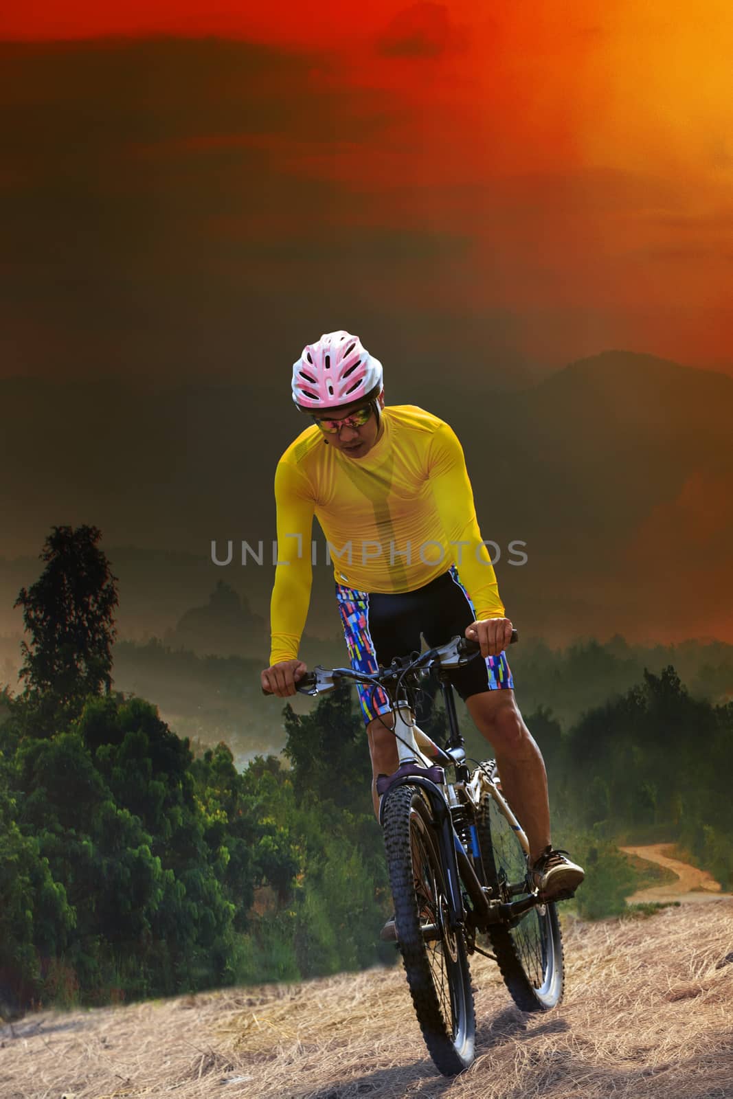 young man riding mountain bike bicycle crossing mountain hill jungle track with dusky sky scene use for out door sport and exteme activities lifestyle