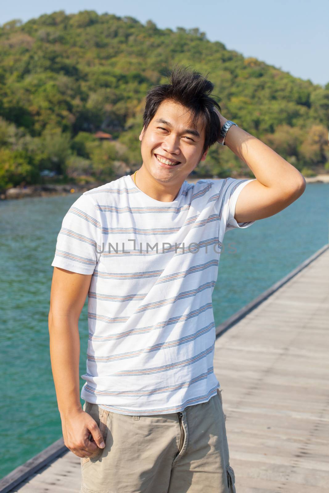 portrait of young asian man standing on wood pier with relaxing  by khunaspix