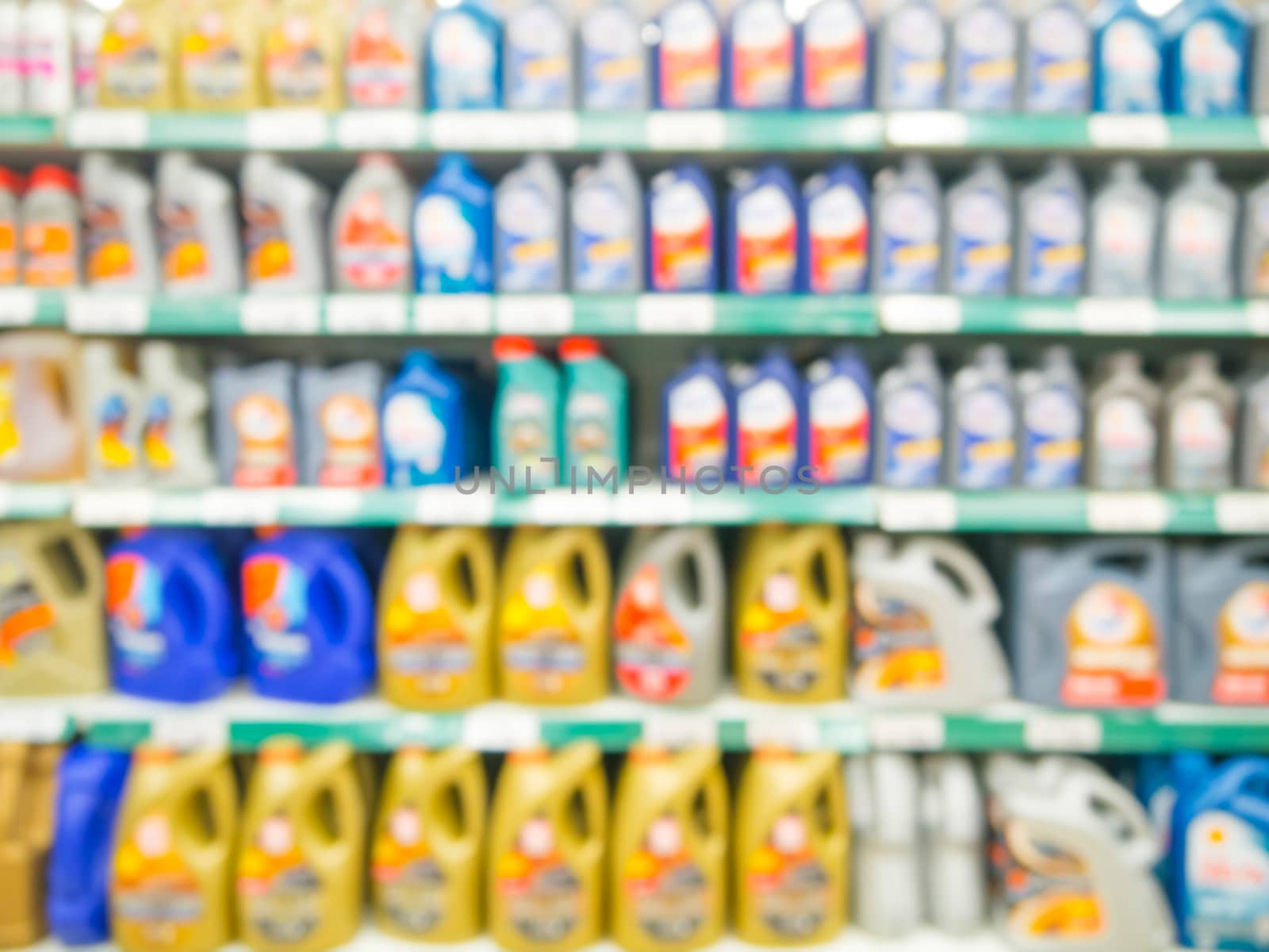 Blurred colorful motor oil bottles on shelves in supermarket as background
