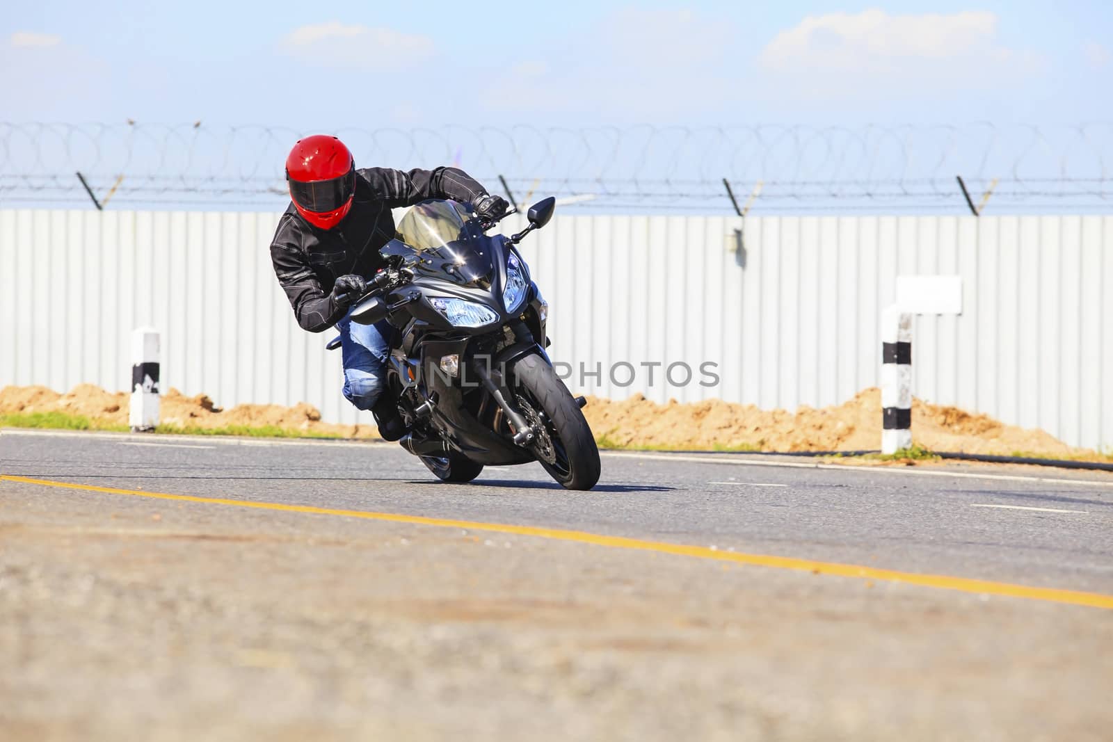 young man riding big bike motorcycle on sharp curve asphalt road by khunaspix
