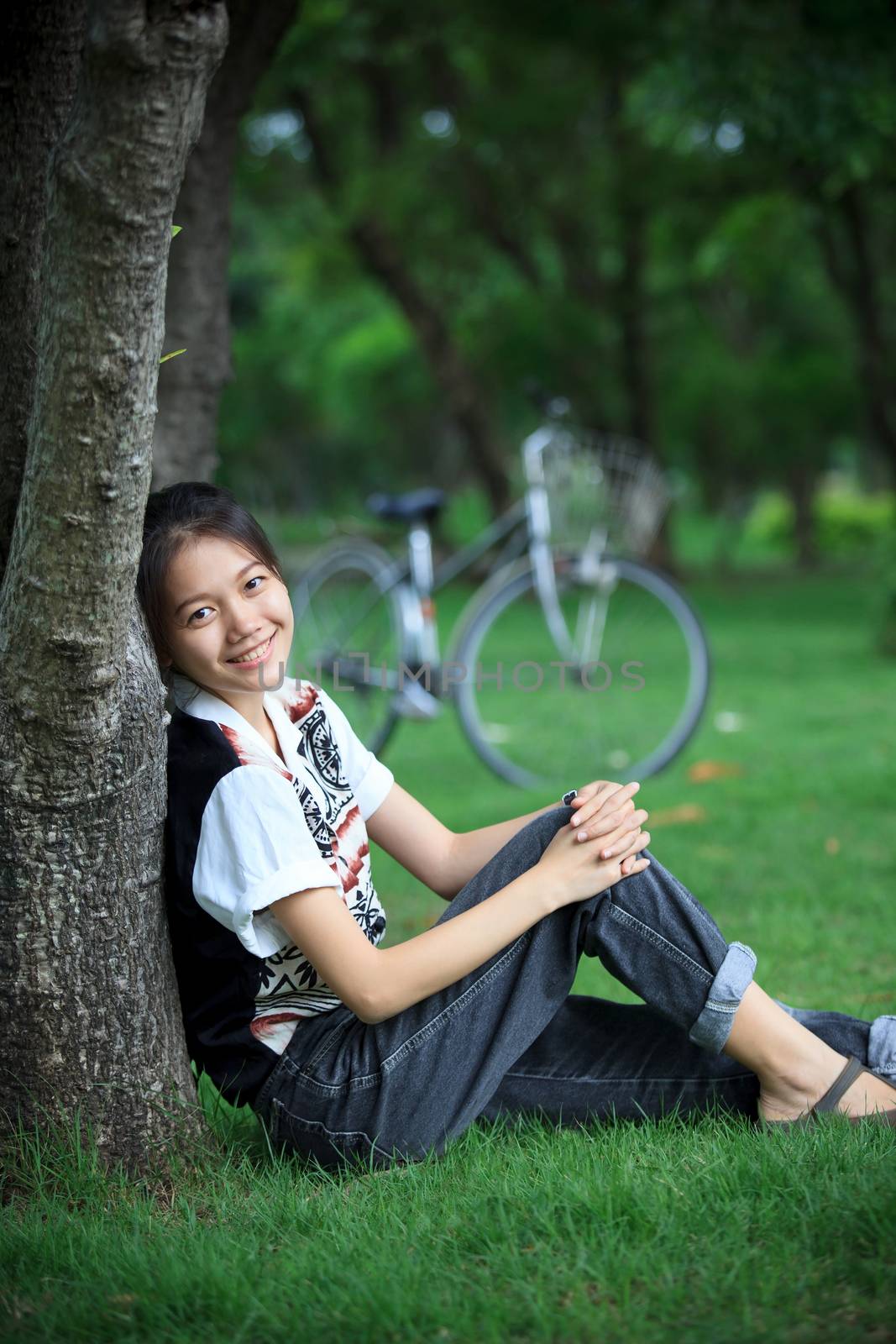 portrait of young woman with blur biclycle background relaxing in green park