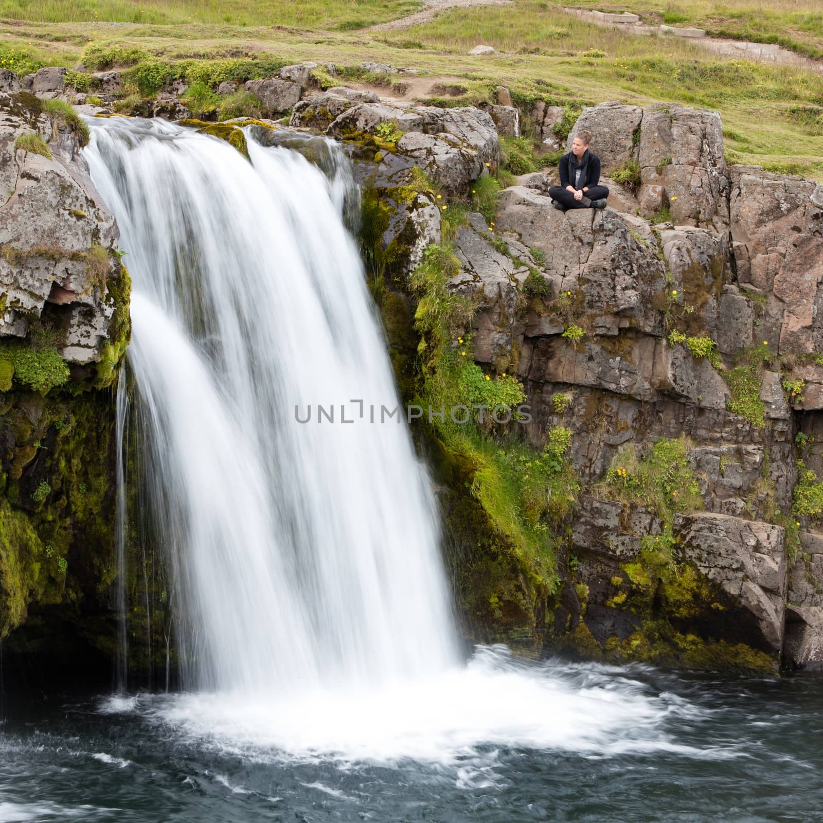 Kirkjufellsfoss waterfall near the Kirkjufell mountain, woman en by michaklootwijk