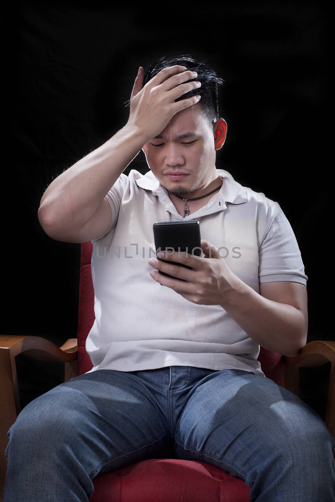 young asian man watching to smart phone screen with unhappy and  by khunaspix