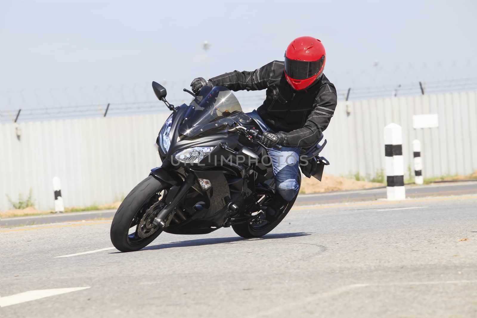 young man wearing safety suit and red anti knock helmet  riding big bike motorcycle running in sharp curve asphalt road use for motor sport activity of rider 
