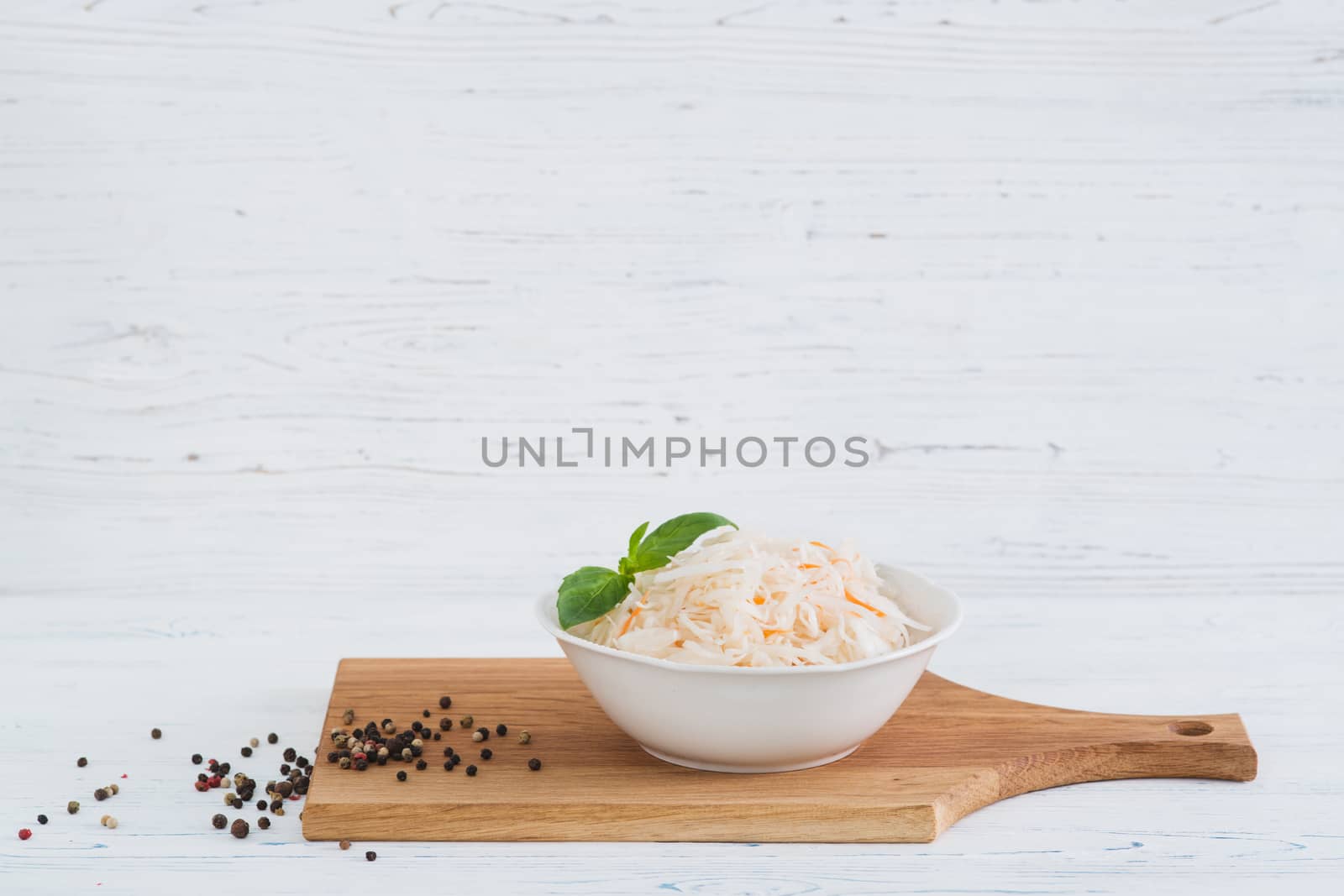 The sauerkraut in bowl, light wooden background