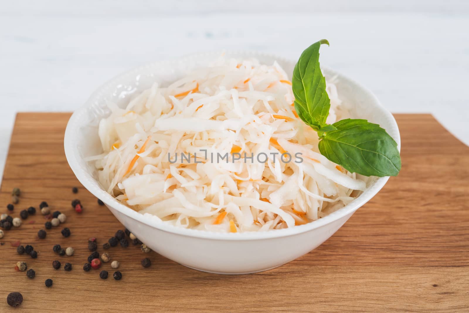 The sauerkraut in bowl, light wooden background