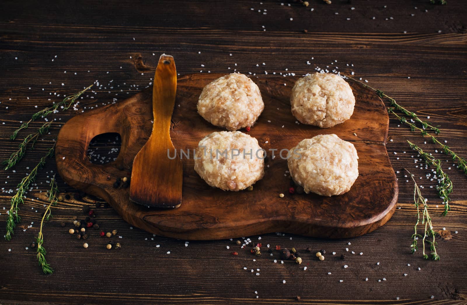 Uncooked meatballs in a dark rustic wooden setting