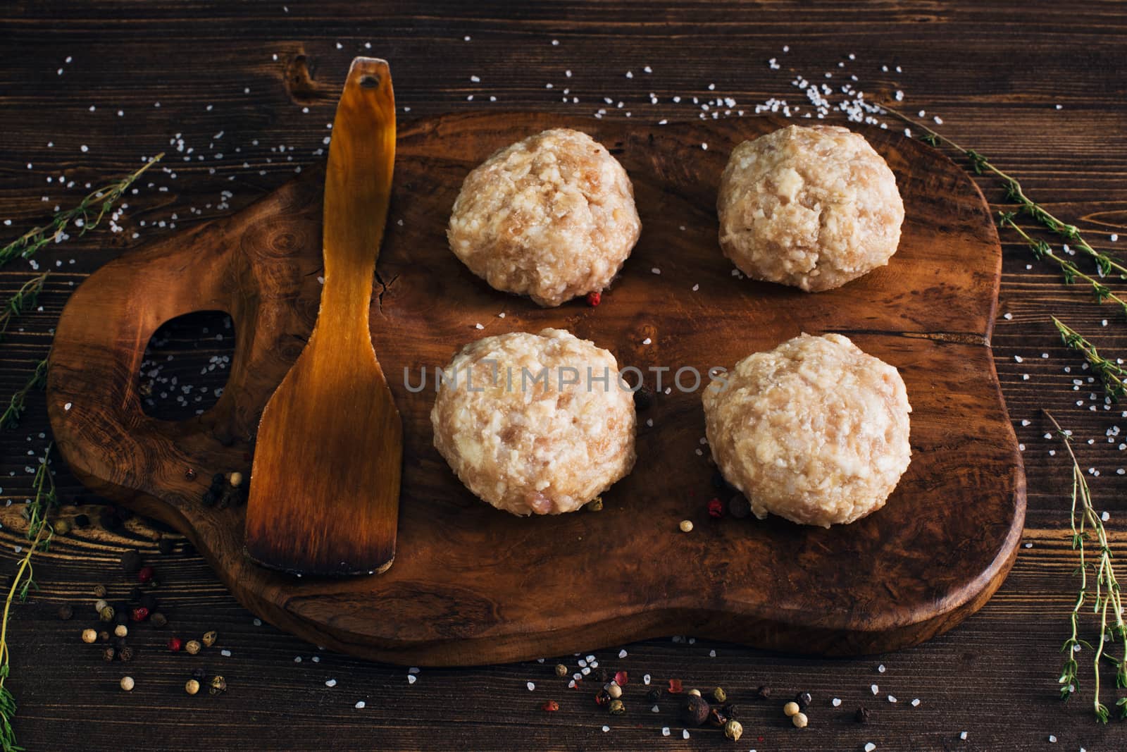 Uncooked meatballs in a dark rustic wooden setting