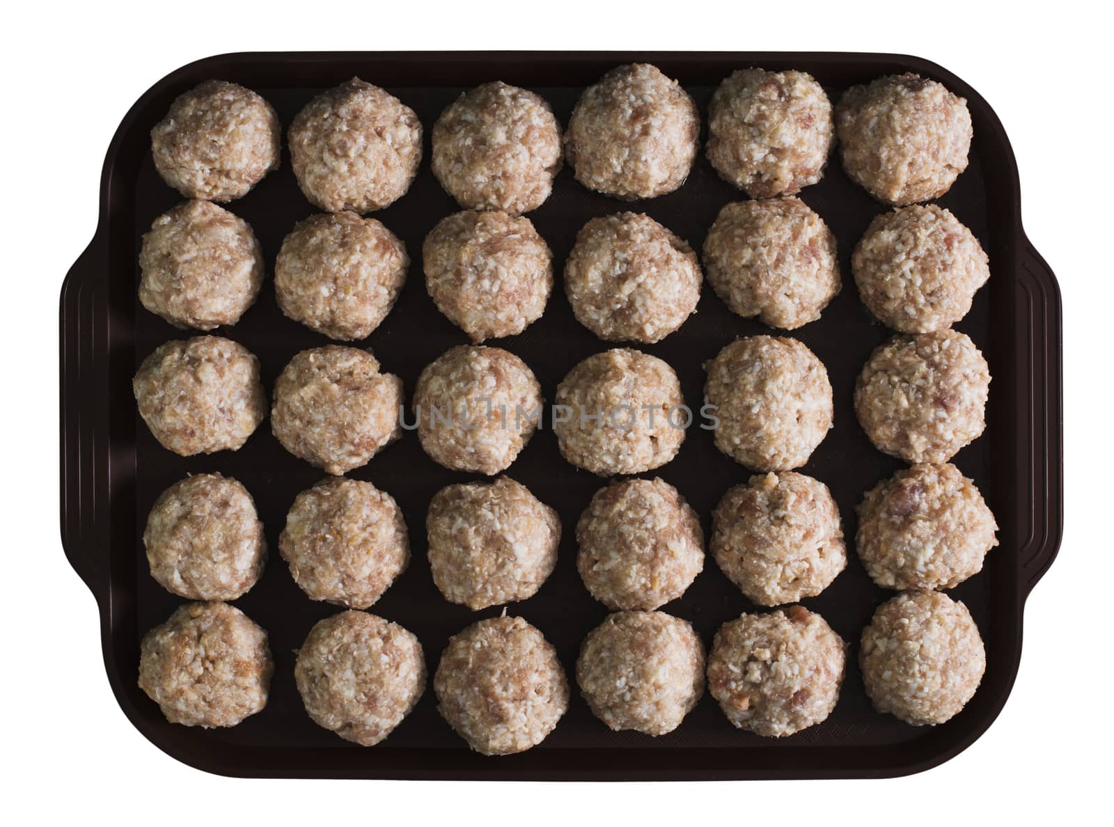 Lots uncooked meatballs on the dark tray, isolated