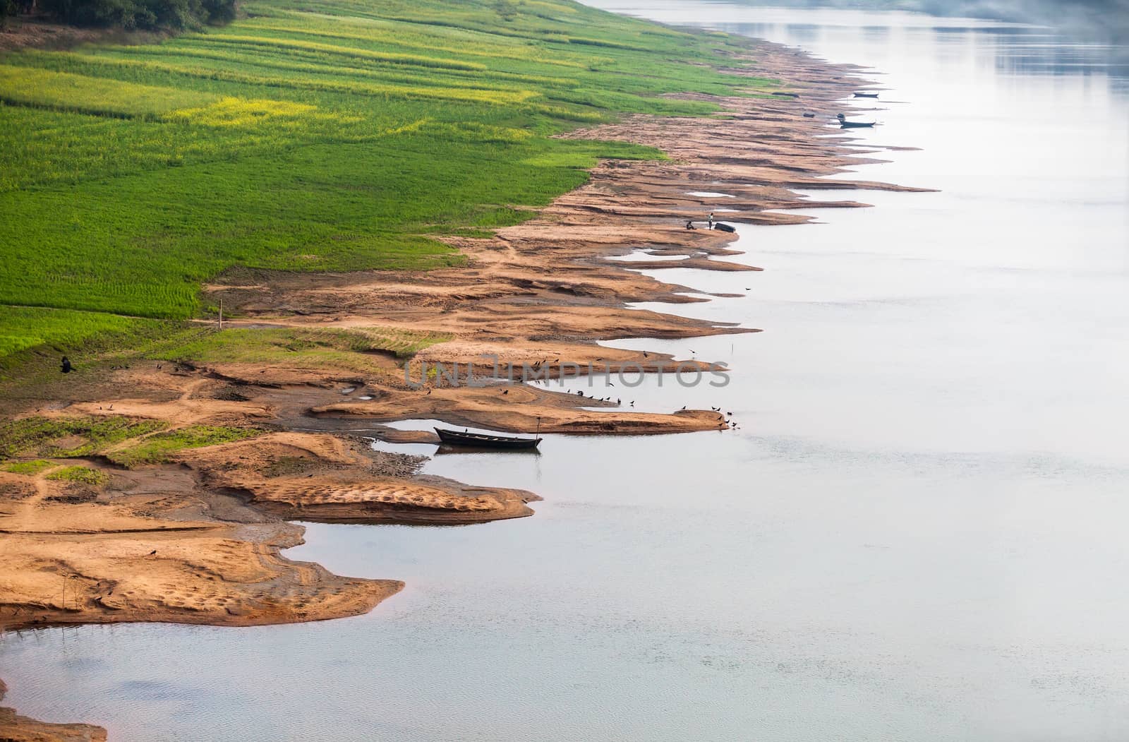 Coastline erosion on the Ganges River. Crops of agricultures in the delta of the river are penetrated by net of gullies. Destruction of the coast is caused by tropical rains. Birds have chosen river shallows and fishing boats.