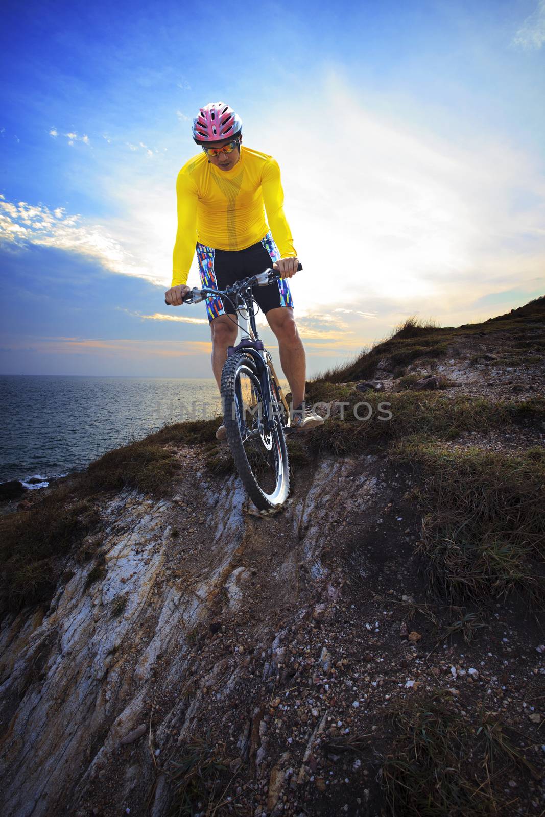 young man riding moutain bike mtb on land dune against dusky sky in evening background use for sport leisure and out door activities theme