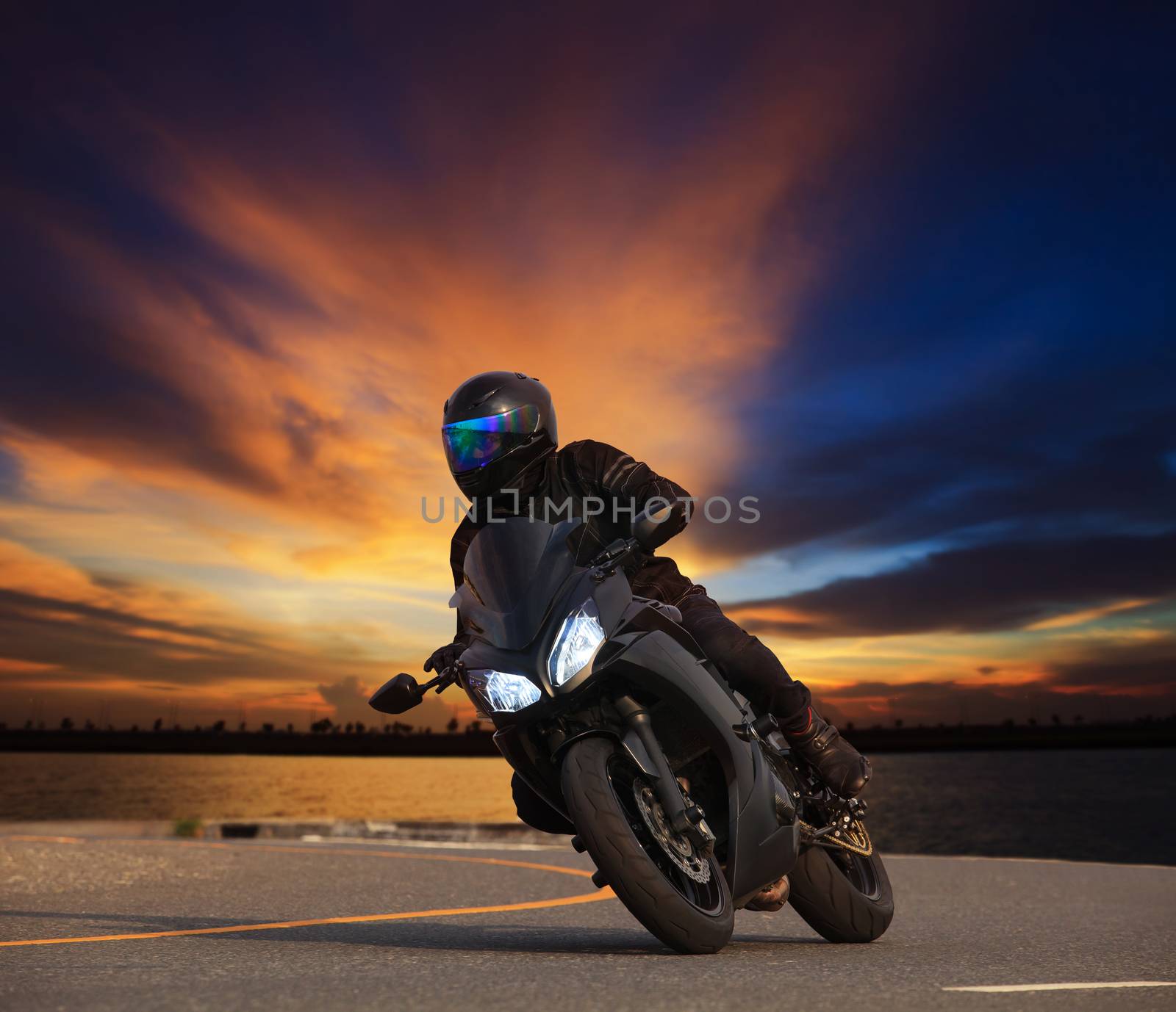 young man riding big bike motorcycle leaning curve on asphalt highways road against beautiful dusky sky use as people adventure sport leisure theme