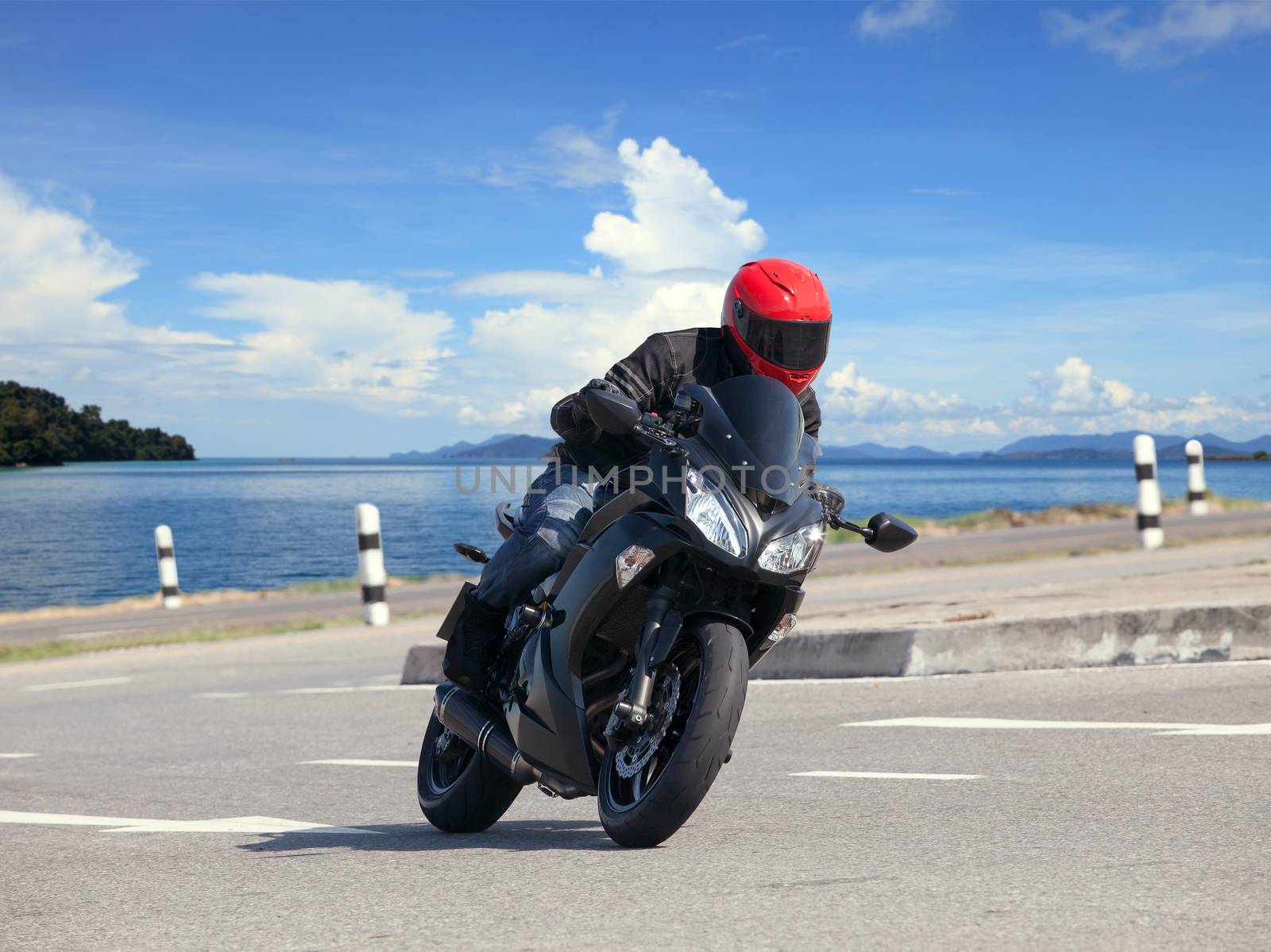 young man riding big bike motorcycle against sharp curve of asphalt high ways road with rural lake scene use for male adventure activities and motor sport hobby on holiday vacation