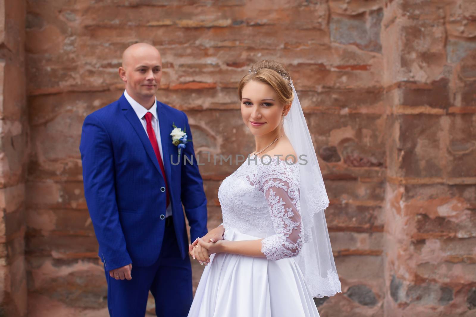 Couple gently embraced on a red brick wall