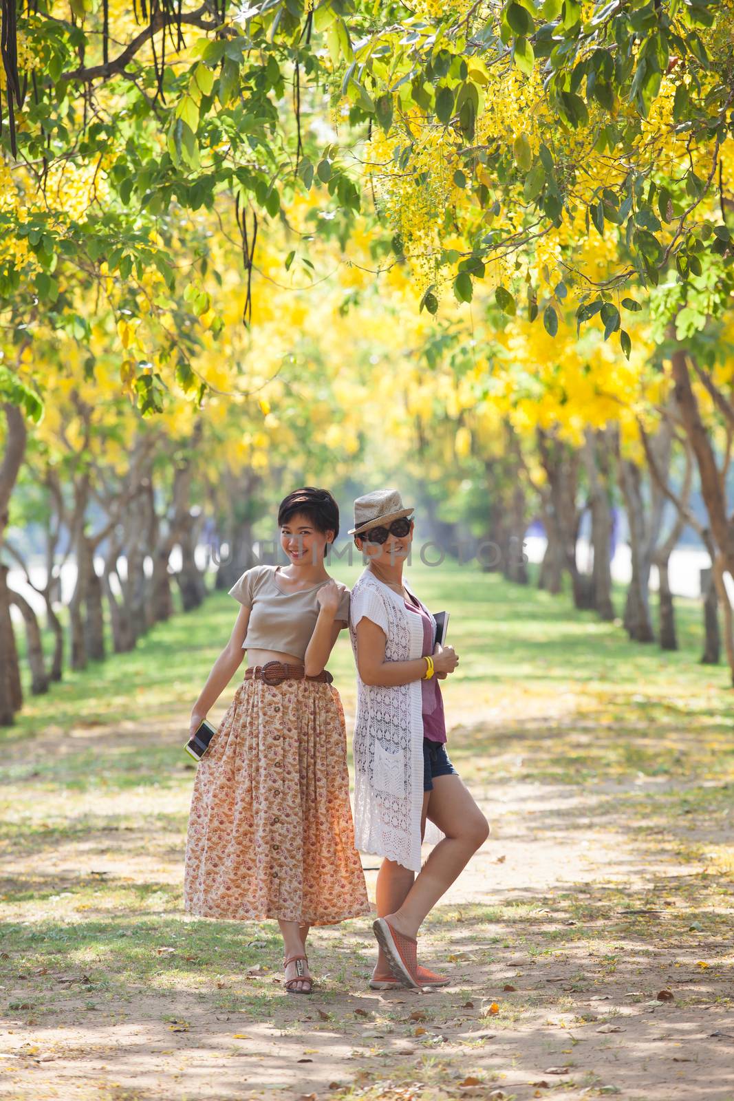 portrait of couples beautiful asian woman standing in blooming flowers park with happieness emotion
