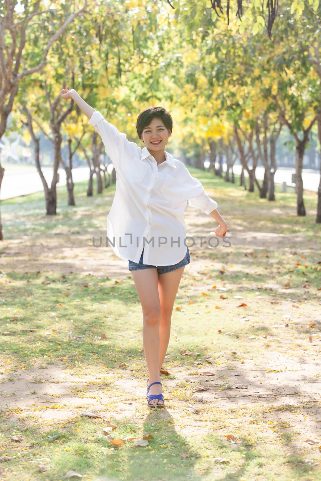 portrait of young beautiful asian woman standing in park with re by khunaspix