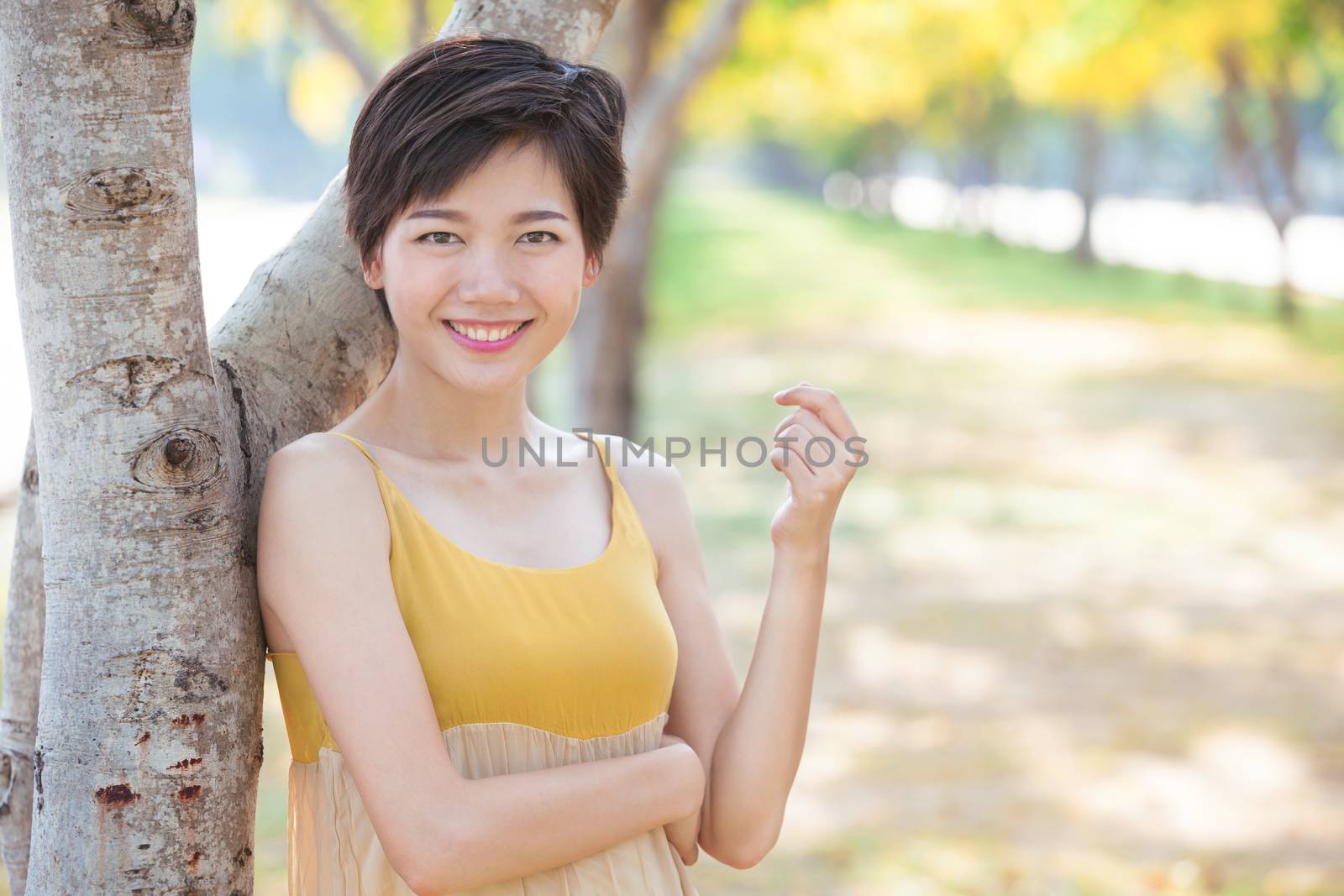 portrait of young beautiful asian woman with short hairs style toothy smiling face with happiness emotion standing in blooming yellow flowers park 
