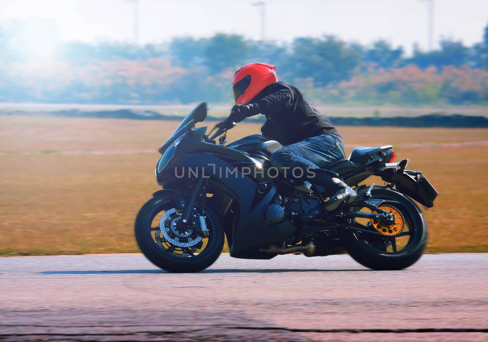 young man riding motorcycle in asphalt road curve with with a moving motion blur photography