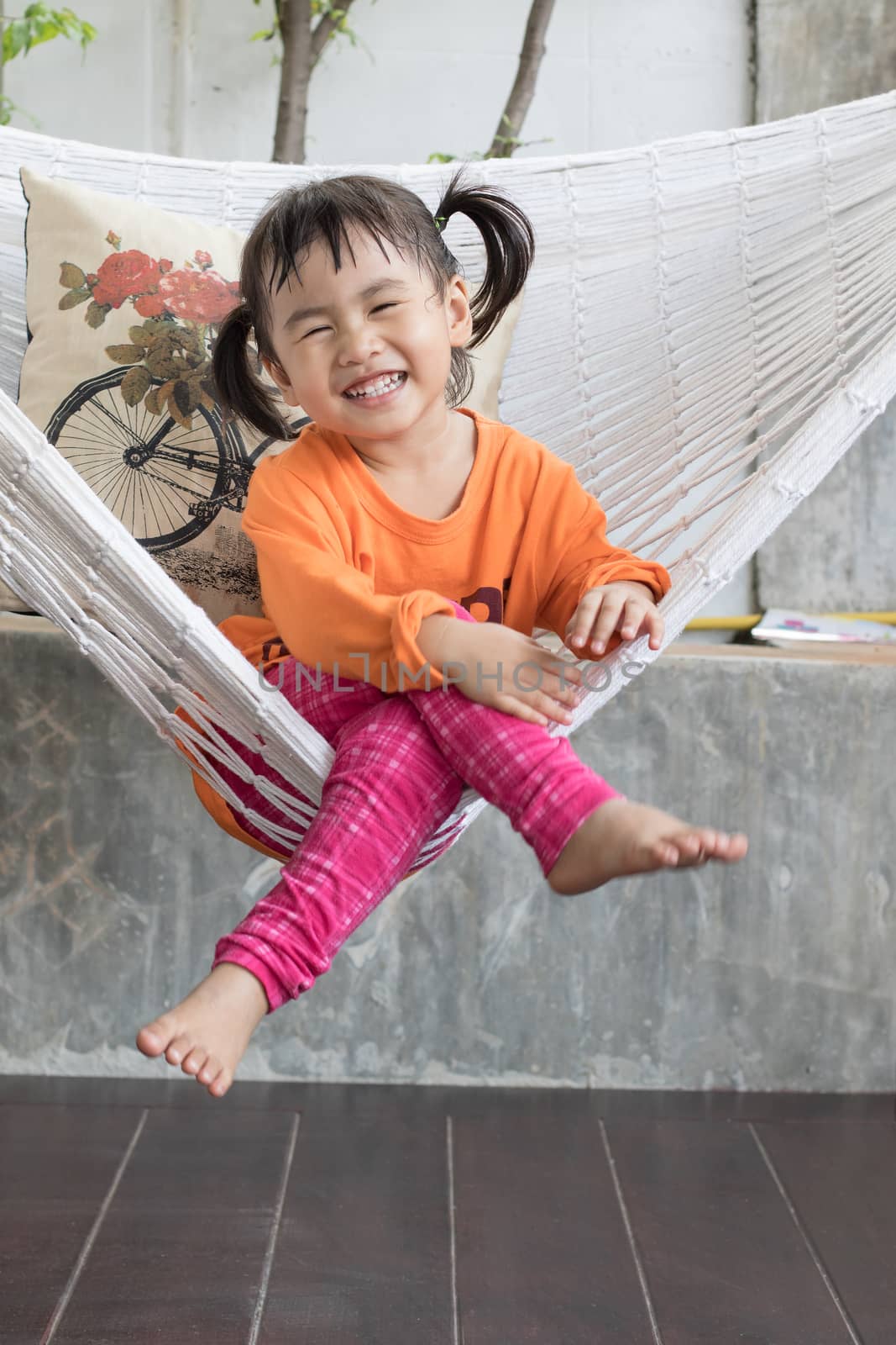 portrait of children toothy smiling and relaxing in clothes cradle at home living terrace