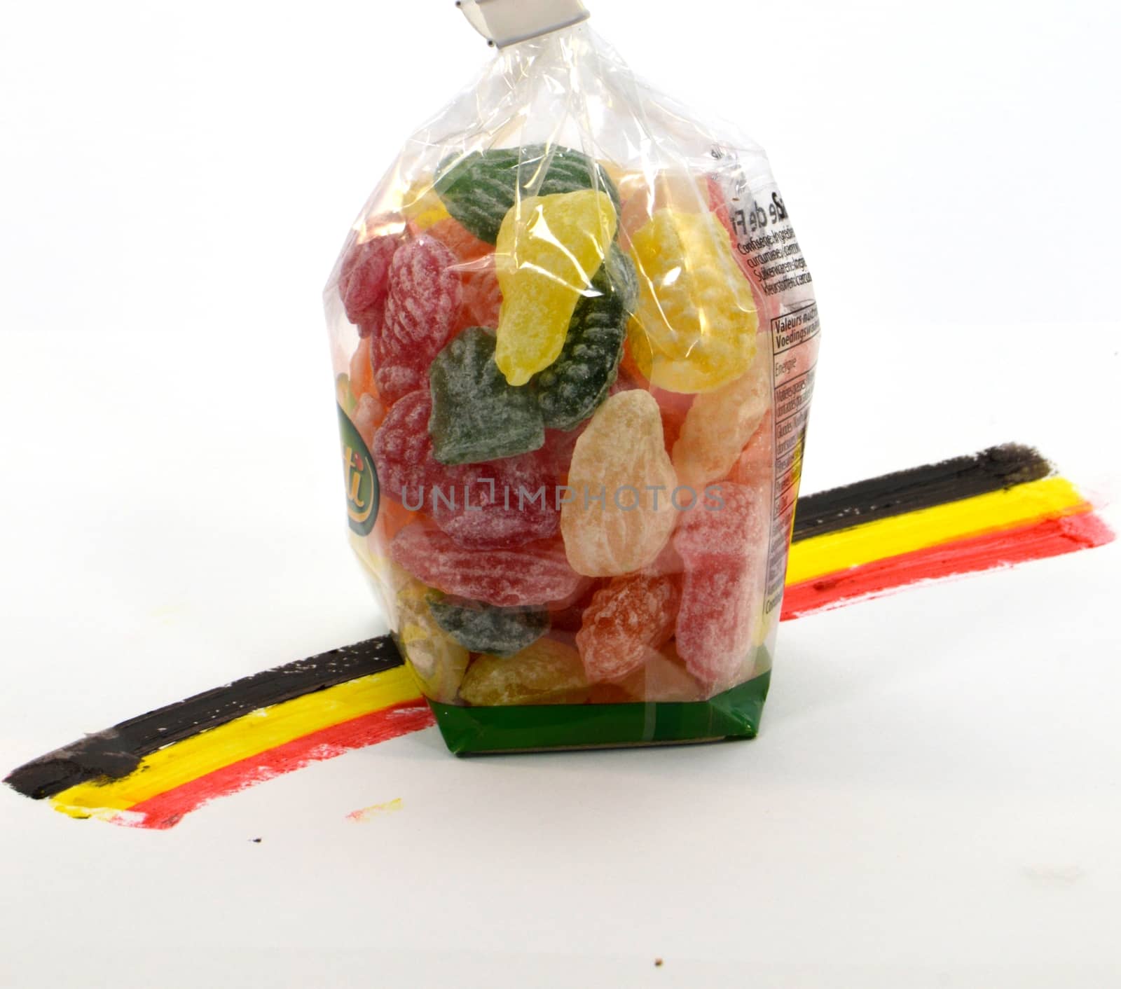 Belgian candy of several colors on and Belgian flags in white background