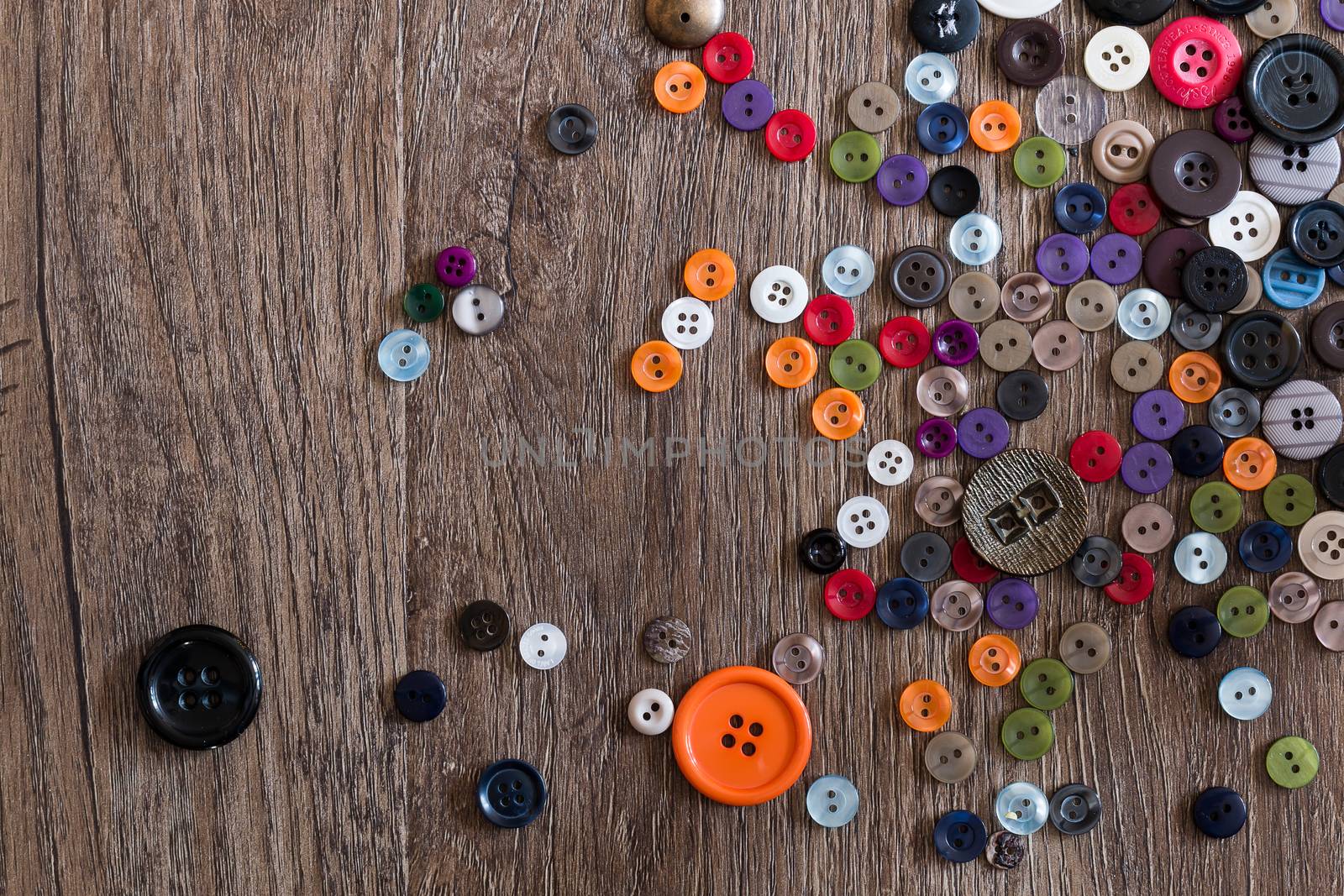 Random Scattering of small multicolored buttons on a wooden floor boards