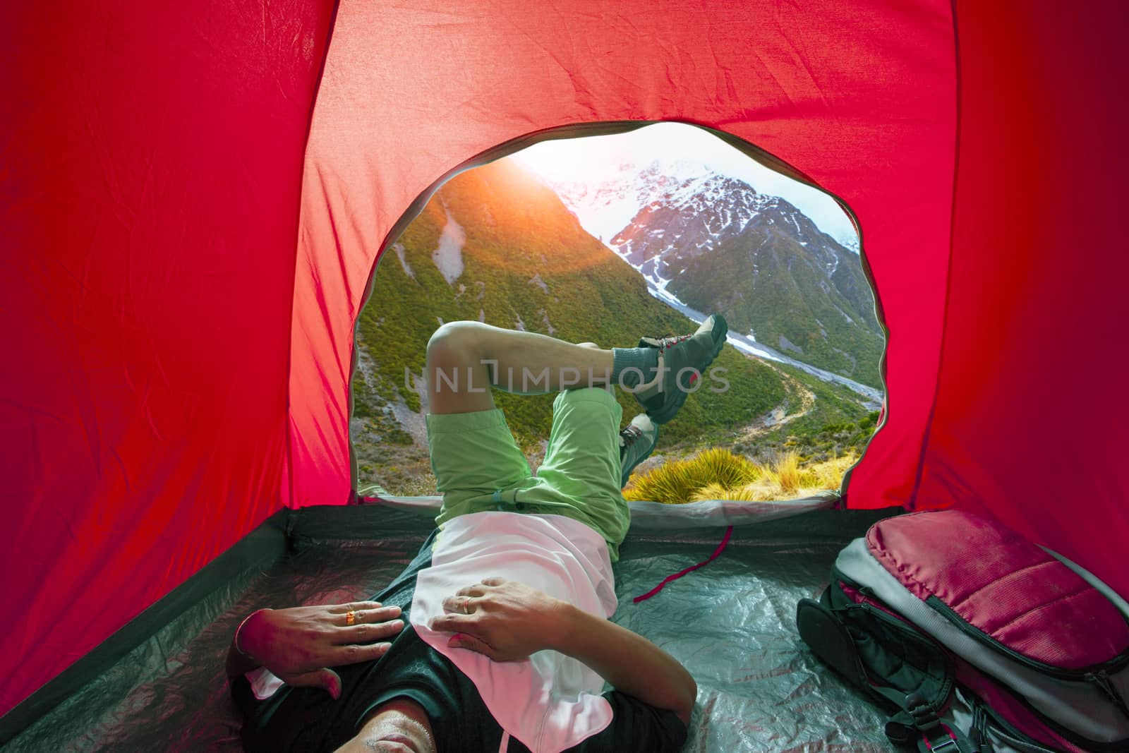 camping man lying in outdoor camping tent with beautiful natural by khunaspix