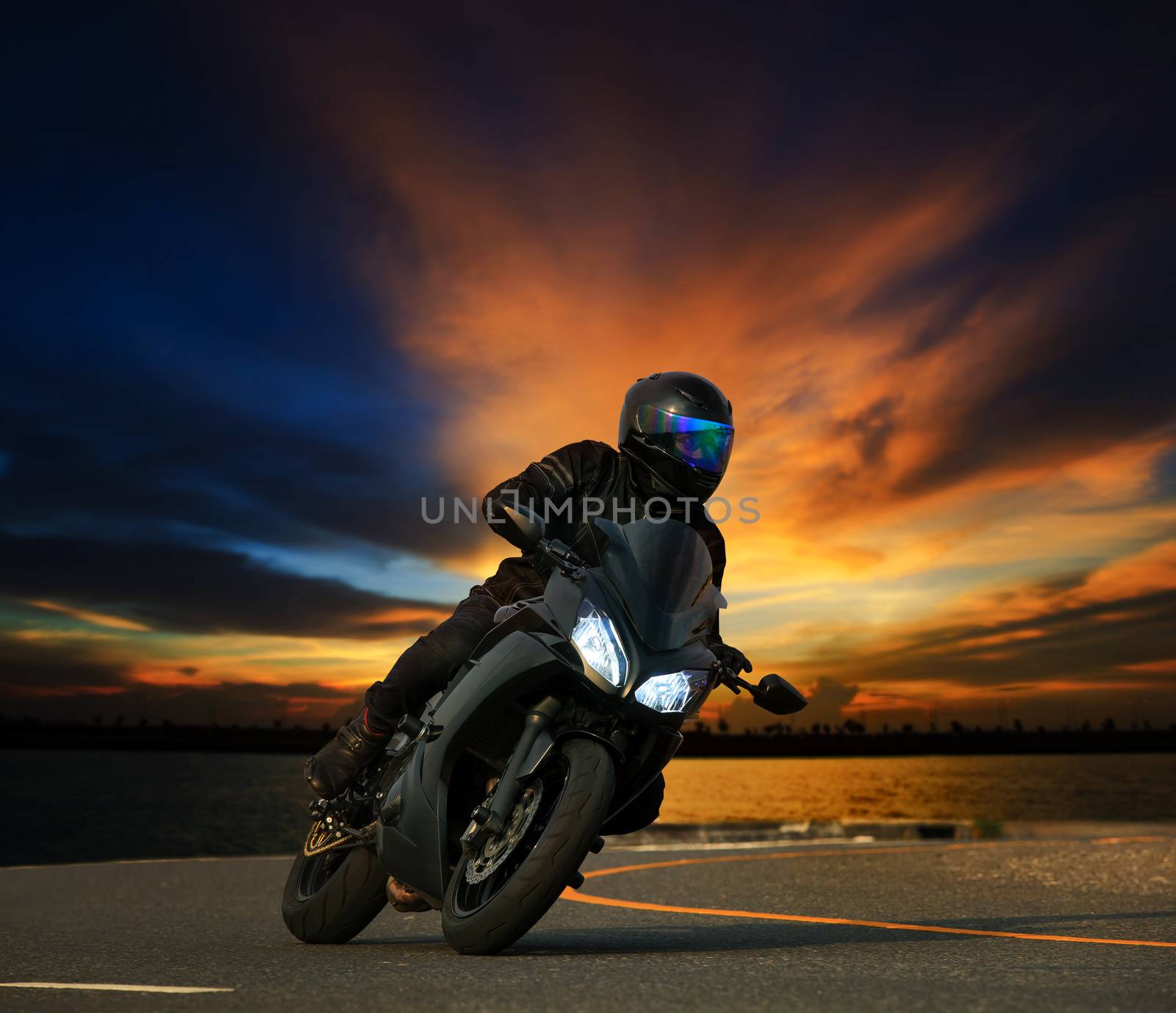 young man riding big bike motorcycle leaning curve on asphalt highways road against beautiful dusky sky use as people adventure sport leisure theme