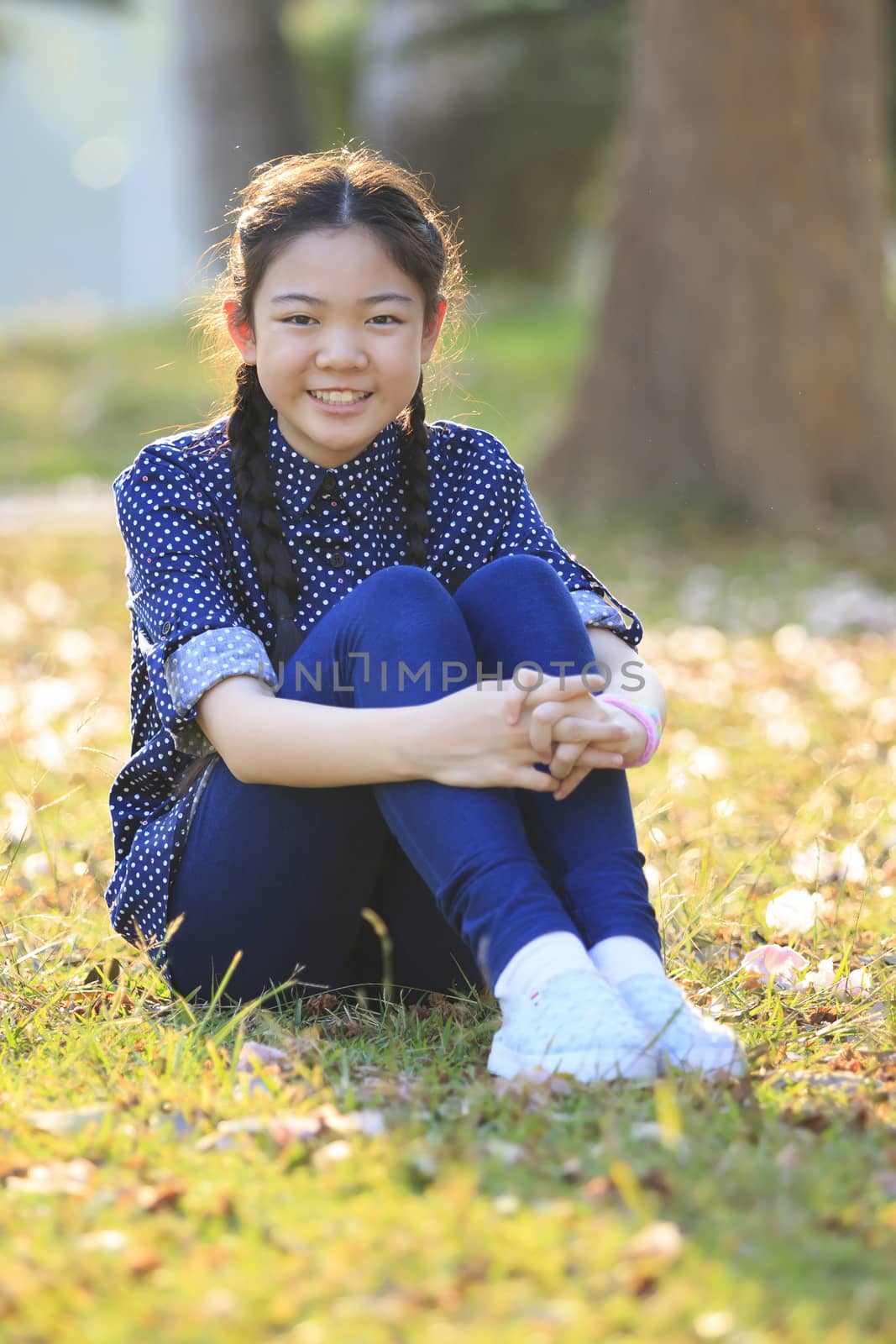 thai 12s years girl sitting on garden field toothy smiling face happiness emotion
