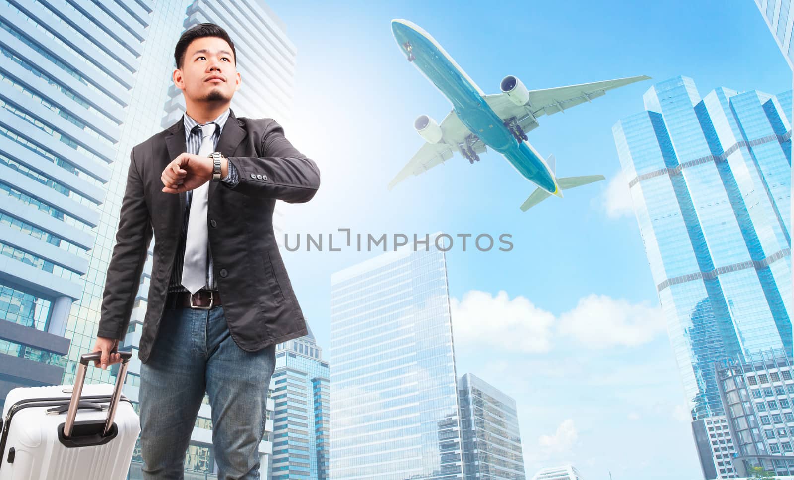 business man and belonging luggage watching to sky and hand watch against high building skyscrapers and passenger plane flying above use for aircraft ,air transportation ,traveling of people theme 