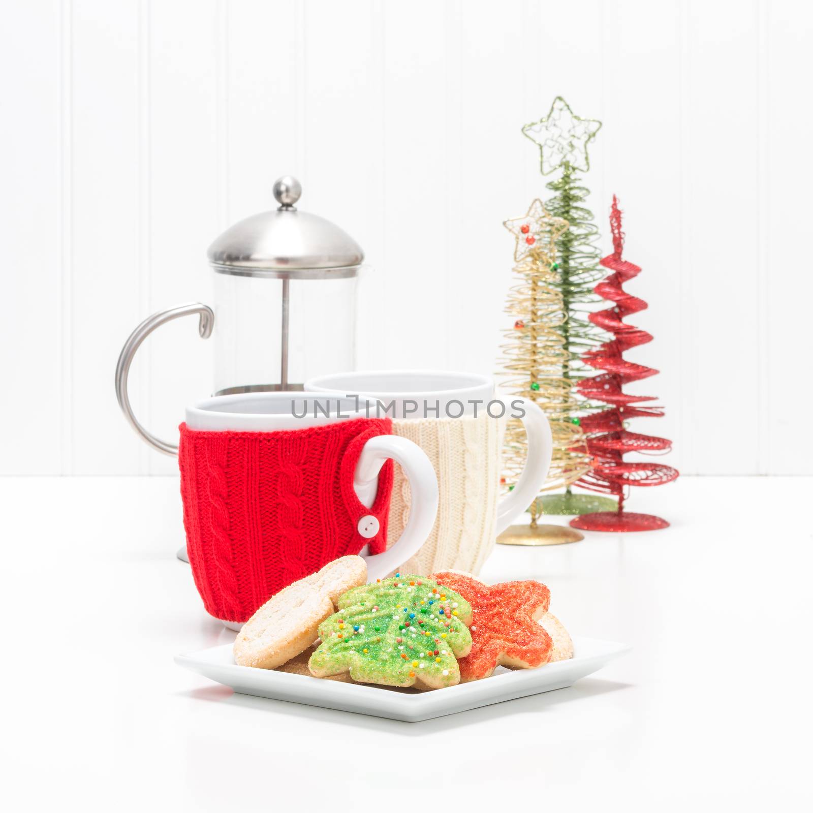 Plate of colorful christmas sugar cookies and cups of coffee.