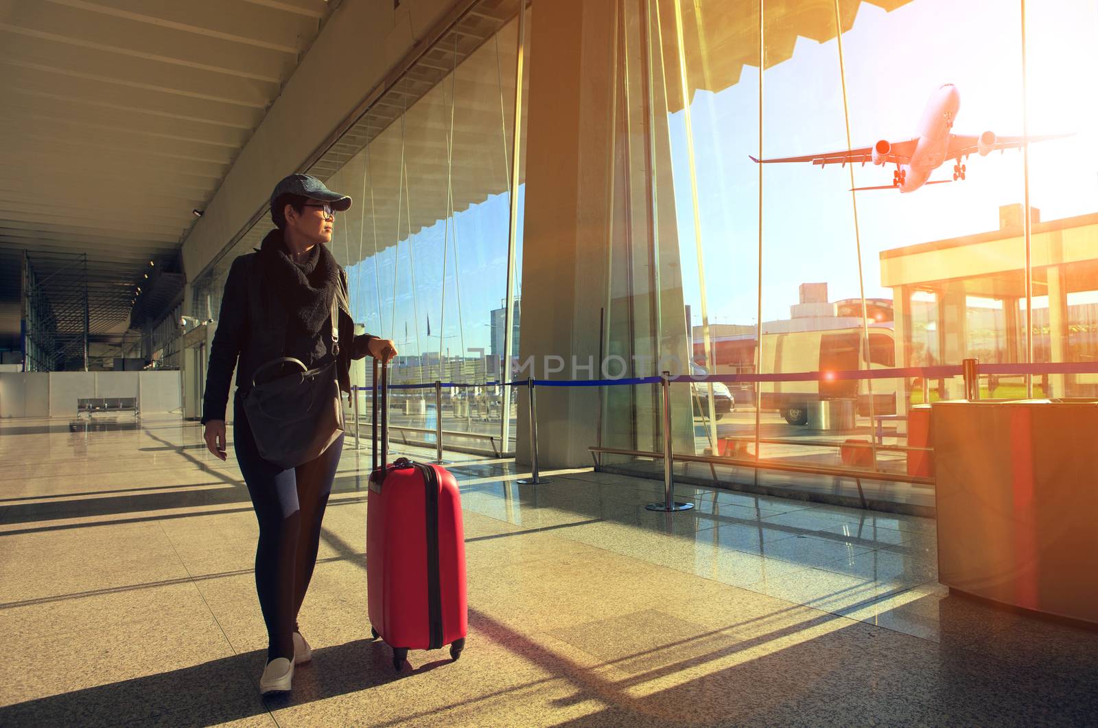 traveling woman and luggage walking in airport terminal and air plane flying outside