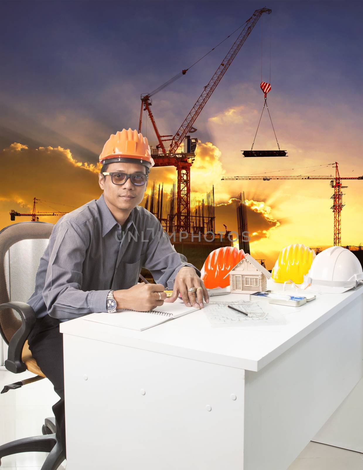 engineering man with safety helmet working table against building construction background