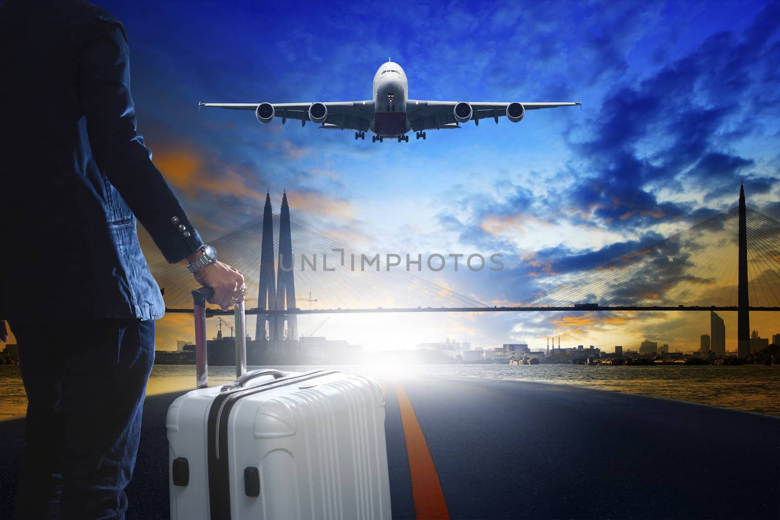 young business man standing with luggage on urban airport runway and jet plane flying above against beautiful urban scen behind