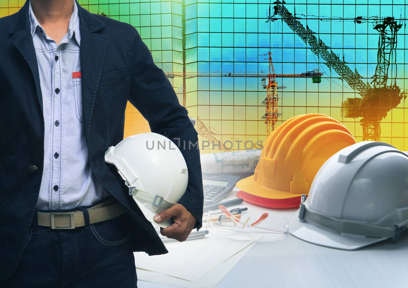 engineering man standing with white safety helmet against building and crane construction working table office use for construction industry business 