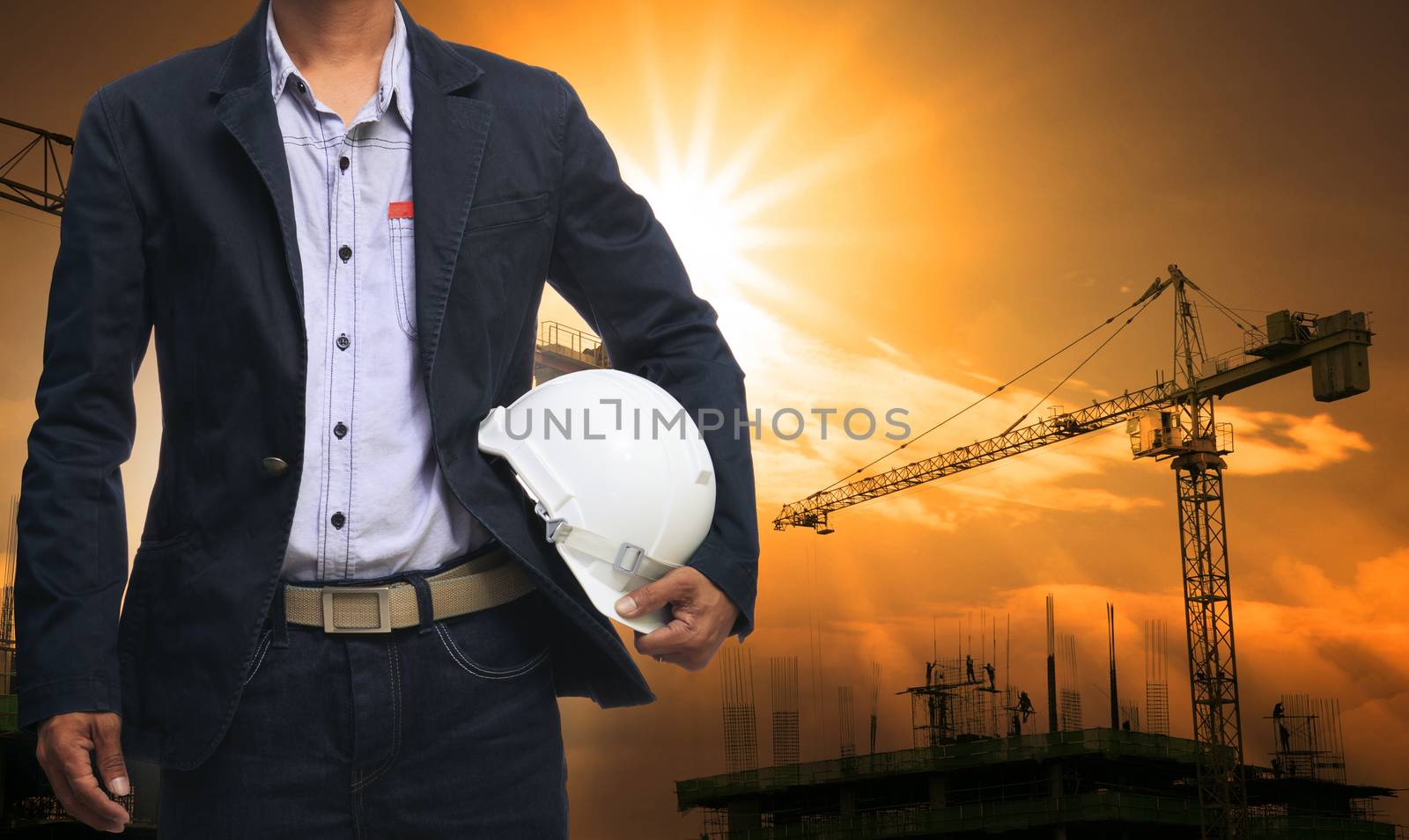 engineer man standing with white safety helmet against beautiful dusky sky with building construction site use for engineering and construction industrial business