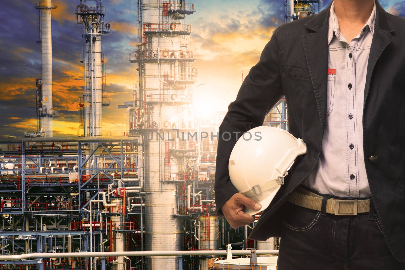 engineering man with white safety helmet standing in front of oil refinery building structure in heavy petrochemical industry 