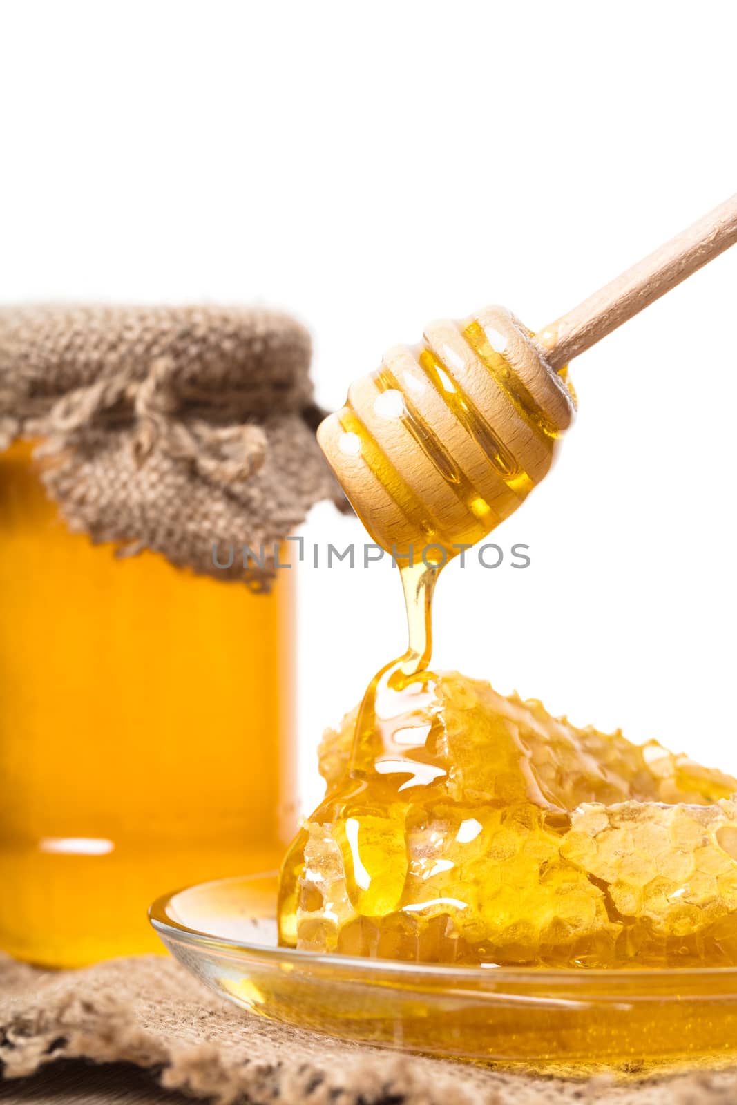 Honey dripping from wooden spoon on a honeycomb